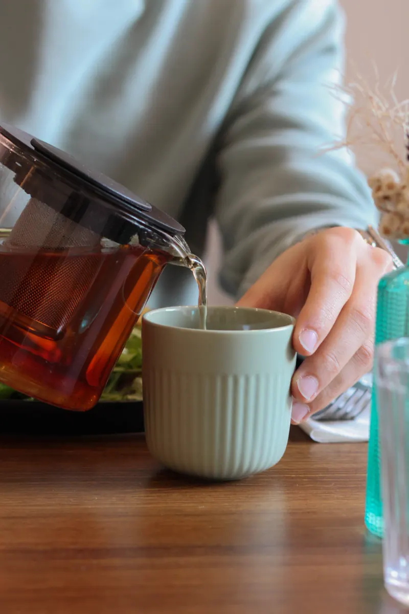 Thé versé d'une théière en verre dans une tasse