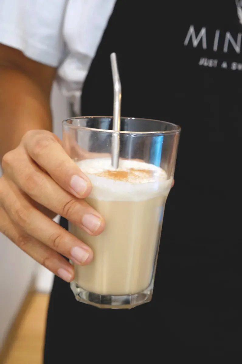 Membre de l'équipe en tablier Minnaya servant un latte glacé