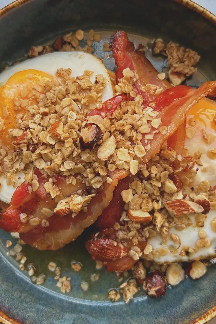 Œufs, bacon et granola dans une assiette bleue