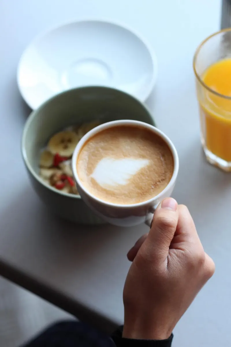 Main tenant un café latte au-dessus d'un bol