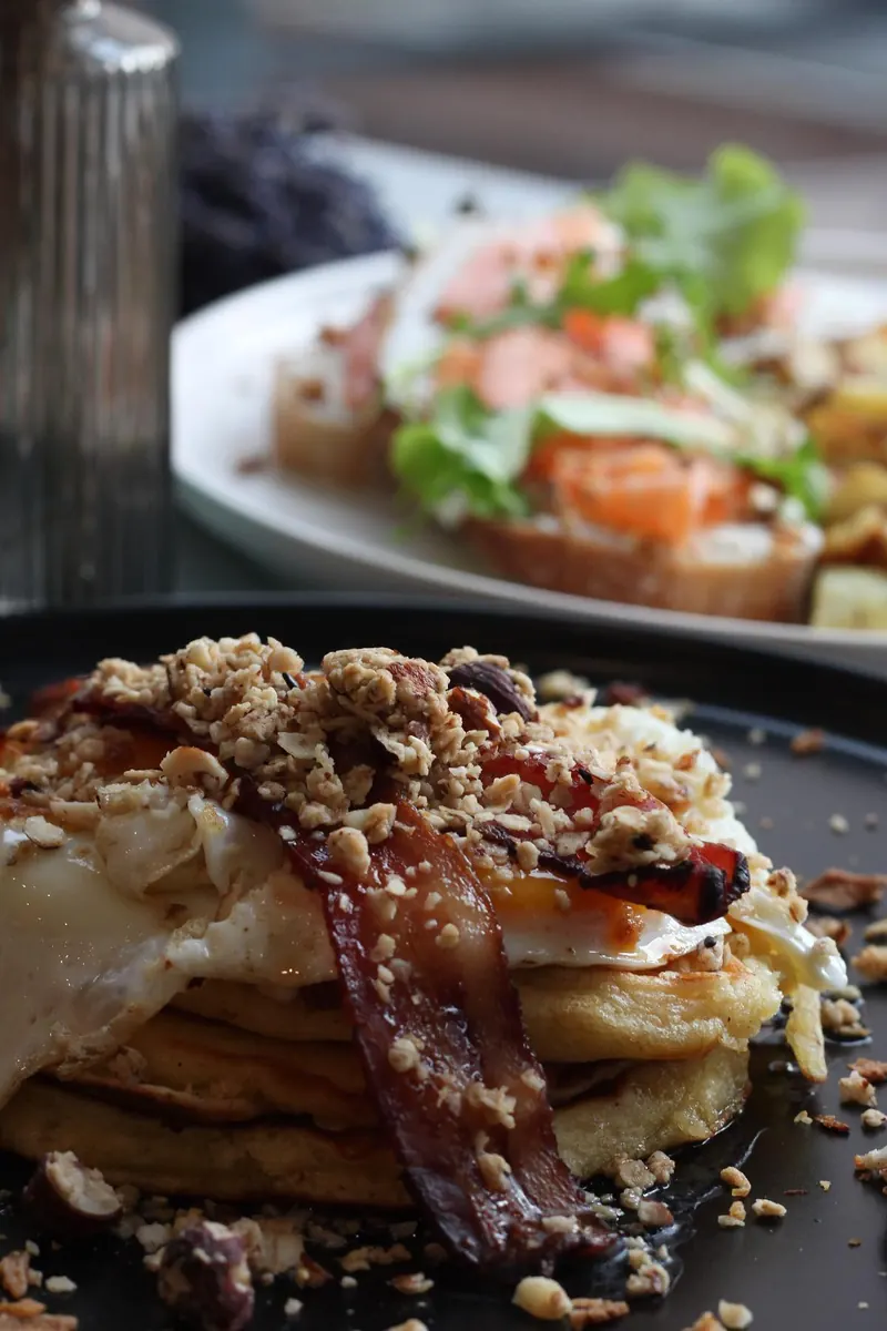 Pancakes au bacon et granola, avocado toast au saumon en arrière-plan